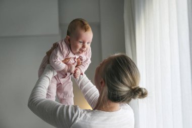 Annem dört aylık pembe pijamalı bir bebeği kucağında tutuyor. Boşluğu kopyala, arkaplan.
