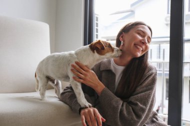 Evde köpeğiyle oynayan genç bir kadın. Boşluğu kopyala, arkaplan.