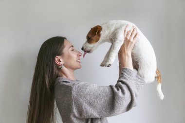 Evde köpeğiyle oynayan genç bir kadın. Boşluğu kopyala, arkaplan.