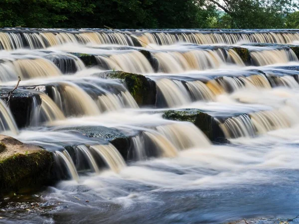 Wharfe Nehri 'nin karşısındaki Burley-in-Wharfedale, İngiltere' de güzel bir giysi. Weir 4 adımda ve nehir hızlı akmadığı için akış yavaşlıyor. Güzel, güneşli bir yaz günü..