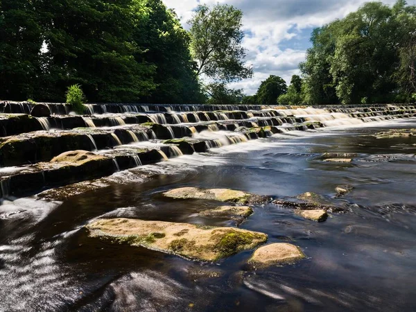 Wharfe Nehri 'nin karşısındaki Burley-in-Wharfedale, İngiltere' de güzel bir giysi. Weir 4 adımda ve nehir hızlı akmadığı için akış yavaşlıyor. Güzel, güneşli bir yaz günü..