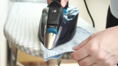 Ütü masasında çocuk taytlarını ütüleyen kadın. Demirden sıcak kökler. Elektrikli ütü tutan kadın, ev işleri. Rutin ev işleri. Yüksek kalite 4k görüntü
