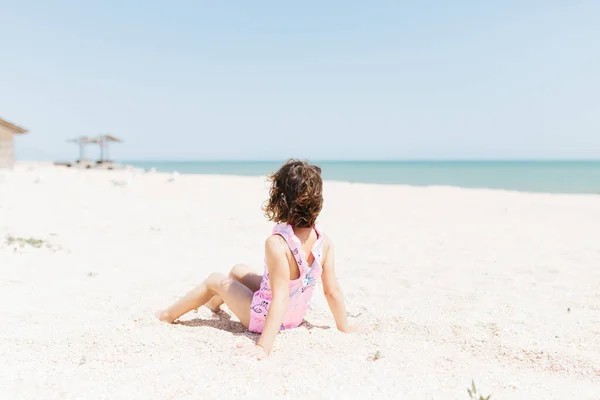 Niña Feliz Con Traje Baño Sentado Playa Durante Día Fotografía —  Fotos de Stock