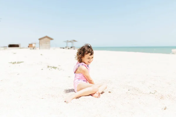 Niña Feliz Con Traje Baño Sentado Playa Durante Día Fotografía —  Fotos de Stock