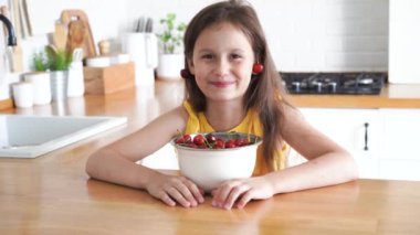 8 yaşında bir kız mutfakta oturmuş kiraz yiyor. Yüksek kalite 4k görüntü