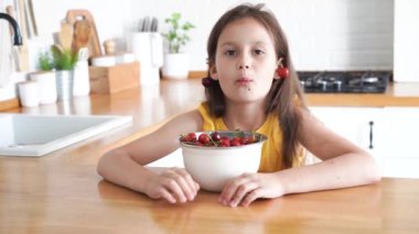 8 yaşında bir kız mutfakta oturmuş kiraz yiyor. Yüksek kalite 4k görüntü