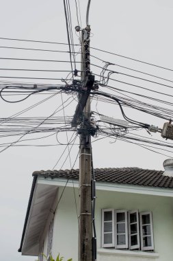 Konutların önünde elektrik direkleri var ama düzensiz bir şekilde düzenlenmiş elektrik kabloları var..