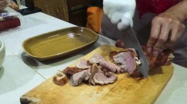Ördek eti, aşçılardan biri tarafından bıçakla parça parça kesiliyor..