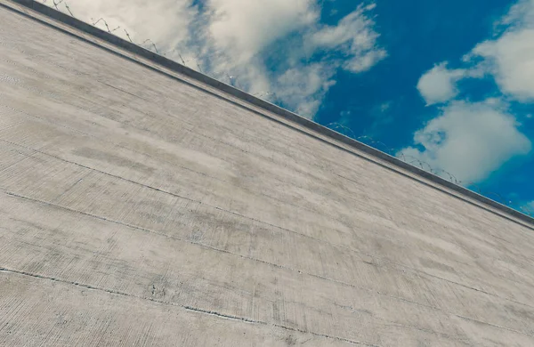 Masivně Vysoká Betonová Bezpečnostní Stěna Ostnatým Drátem Pozadí Modré Oblohy — Stock fotografie