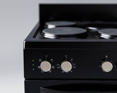 İzole edilmiş arka planda siyah, markasız, serbest çalışan bir ev sobası ve fırın mutfak gereçleri ünitesinin yakın plan bölümü.