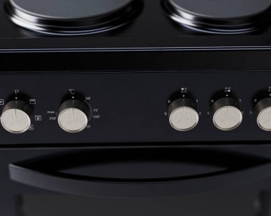 İzole edilmiş arka planda siyah, markasız, serbest çalışan bir ev sobası ve fırın mutfak gereçleri ünitesinin yakın plan bölümü.