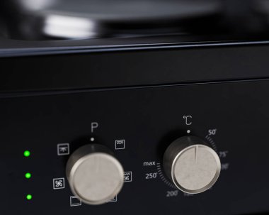 İzole edilmiş arka planda siyah, markasız, serbest çalışan bir ev sobası ve fırın mutfak gereçleri ünitesinin yakın plan bölümü.