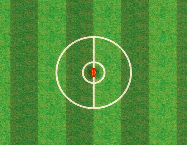 スタジアムの中央線にある赤いオージーのルールボールで ライトアップされた照明の下で夜に緑色の芝生のピッチに投稿されます — ストック写真