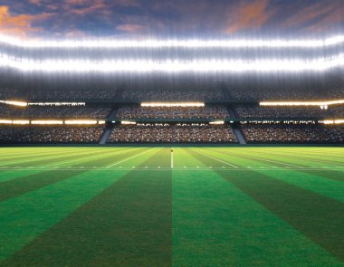 İşaretli yeşil çimenlik bir sahada geceleri ışıklandırılmış projektörlerin altında direkleri olan bir Amerikan futbol stadyumu.