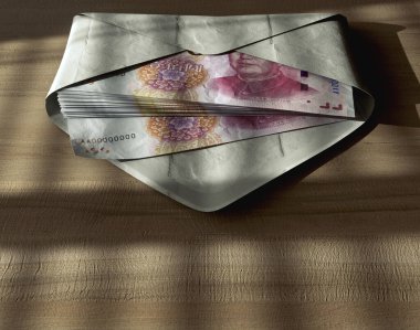 Huysuz ışıklandırma altında ahşap bir yüzey üzerinde bir zarf içinde yayılan Çin Yuan banknotları.