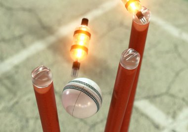 Beyaz bir kriket topu turuncu elektronik kriket kalelerine çarpıyor ve gece arkaplanındaki LED ışıkları yakıyor.