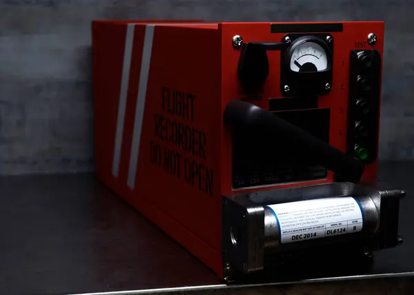 stock image A regular aviation flight recorder black box painted in orange on metal shelf in a dark room - 3D render
