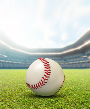 Sıradan bir beyzbol stadyumu, gündüz vakti yeşil çimlerin üzerinde bir beyzbol topunu mavi bulutlu gökyüzünün altında gösteriyor.