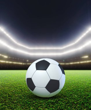 Bir futbol stadyumu, gece yeşil çimlerin üzerinde yanan projektörlerin altında bir futbol topunu gösteriyor.