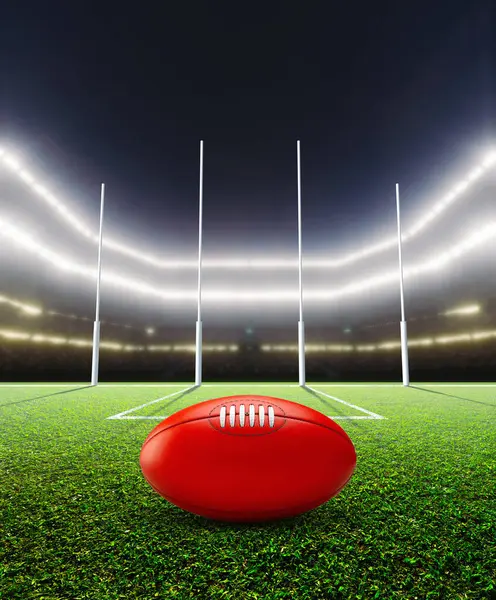 stock image A generic seated aussie rules stadium showing goal posts and a ball on a green grass pitch at night under illuminated floodlights - 3D render