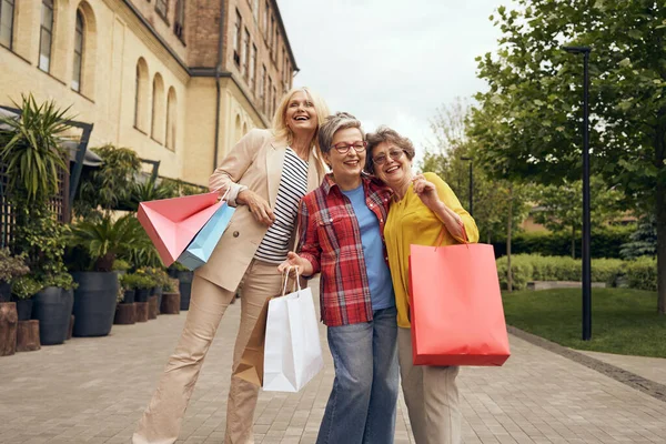 Joyful old women friends after shopping having fun while walking outdoors