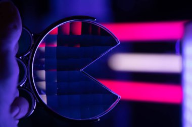 A beautiful glass fractal prism held in front of colorful LED lights. Glass reflections of light.