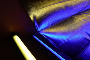 A beautiful, reflective photo umbrella surface in blue and yellow lights. Photo studio equipment with led light.