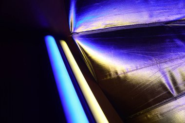 A beautiful, reflective photo umbrella surface in blue and yellow lights. Photo studio equipment with led light.