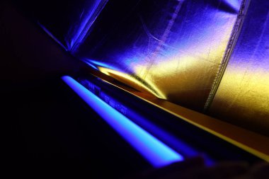 A beautiful, reflective photo umbrella surface in blue and yellow lights. Photo studio equipment with led light.