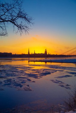 Güzel, renkli bir gün doğumu manzarası. Şehir merkezi silueti parlak sabah gökyüzüne karşı. Letonya 'nın başkenti Riga' da donmuş Daugava nehri ile bir kış lansdpelerini..