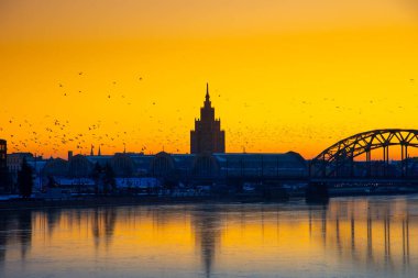 Güzel, renkli bir gün doğumu manzarası. Şehir merkezi silueti parlak sabah gökyüzüne karşı. Letonya 'nın başkenti Riga' da donmuş Daugava nehri ile bir kış lansdpelerini..