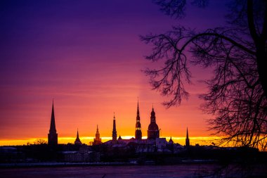 Güzel, renkli bir gün doğumu manzarası. Şehir merkezi silueti parlak sabah gökyüzüne karşı. Letonya 'nın başkenti Riga' da donmuş Daugava nehri ile bir kış lansdpelerini..