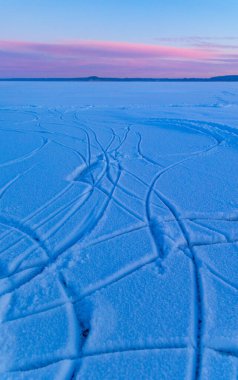 Donmuş gölü ve karda izleri olan güzel bir gündoğumu manzarası. Kuzey Avrupa 'da kış manzarası ve gökyüzü.