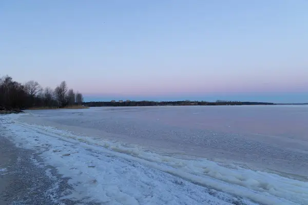 A beautiful minimalist landscape of frozen lake with a horizon in the distance. Winter scenery of Northern Europe.