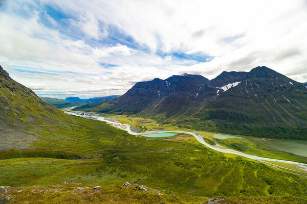 A beautiful summer landscape with Rapa river Rapadalen in Sarek National Park in Sweden. A mountain river from above. Wild scenery of Northern Europe.