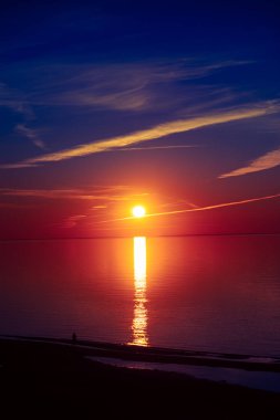 Baltık Sahili 'nde akşamın tadını çıkaran güzel bir gün batımı manzarası. Kuzey Avrupa 'da denize karşı insan siluetleri.