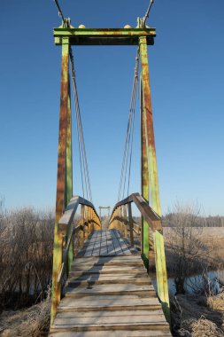 Nehrin üzerinde ahşap yürüyen köprüsü olan erken bahar manzarası. Kuzey Avrupa 'da doğal kırsal manzara.