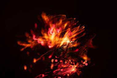 Karanlık gökyüzünde yılbaşı havai fişeklerinin sanatsal bir resmi. Uzun pozlama, bokeh, çekimser. Kutlamanın renkli ve soyut bir resmi.