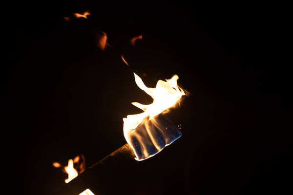 Красивый крупный план горящего факела с огненным пламенем во время летнего фестиваля. Яркий огонь ночью.