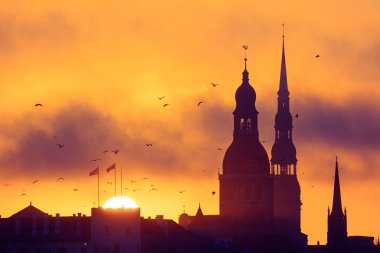 Gün doğumunda Letonya, Riga 'nın güzel bir manzarası. Renkli gökyüzüne karşı kilise kuleleri. Sabahları binalarla dolu bir panorama..