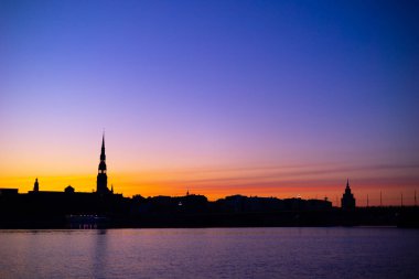 Gün doğumunda Letonya, Riga 'nın güzel bir manzarası. Renkli gökyüzüne karşı kilise kuleleri. Sabahları binalarla dolu bir panorama..