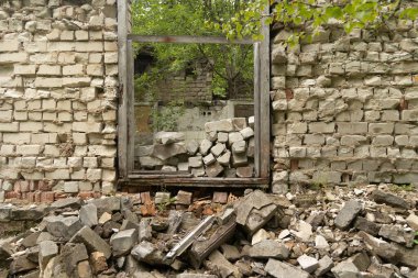 Sovyet döneminden kalma, yıkık dökük, boş bir bina penceresi. Pencereli tuğla duvar çökmüş. Letonya, Avrupa.