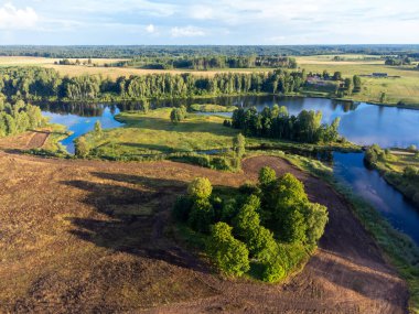 Küçük bir gölün güzel bir yaz manzarası, yeşil ağaçlar ve tarlalar, bir drondan alındı. Letonya 'nın doğal kırsal manzarası, Kuzey Avrupa.