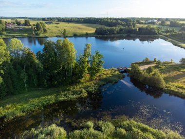 Küçük bir gölün güzel bir yaz manzarası, yeşil ağaçlar ve tarlalar, bir drondan alındı. Letonya 'nın doğal kırsal manzarası, Kuzey Avrupa.