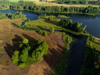 Küçük bir gölün güzel bir yaz manzarası, yeşil ağaçlar ve tarlalar, bir drondan alındı. Letonya 'nın doğal kırsal manzarası, Kuzey Avrupa.