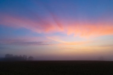 Renkli gündoğumu gökyüzüne sahip güzel bir minimalist manzara. Letonya kırsalının parlak yaz manzarası, Kuzey Avrupa.