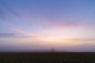 Renkli gündoğumu gökyüzüne sahip güzel bir minimalist manzara. Letonya kırsalının parlak yaz manzarası, Kuzey Avrupa.