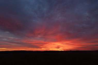 Renkli gündoğumu gökyüzüne sahip güzel bir minimalist manzara. Letonya kırsalının parlak yaz manzarası, Kuzey Avrupa.