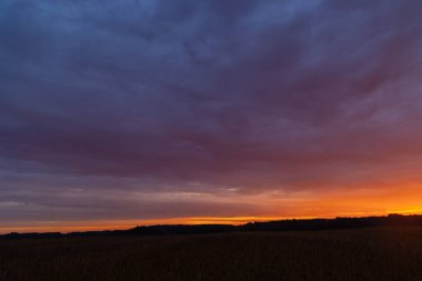 Renkli gündoğumu gökyüzüne sahip güzel bir minimalist manzara. Letonya kırsalının parlak yaz manzarası, Kuzey Avrupa.