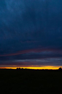 Renkli gündoğumu gökyüzüne sahip güzel bir minimalist manzara. Letonya kırsalının parlak yaz manzarası, Kuzey Avrupa.